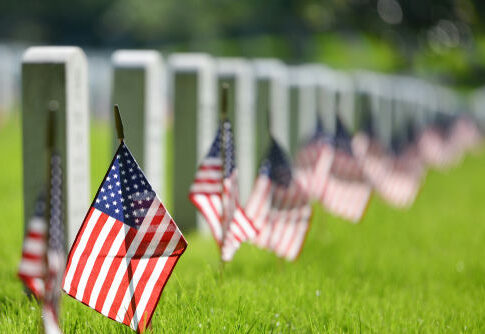 American flags beside gravestones in a cemetery.