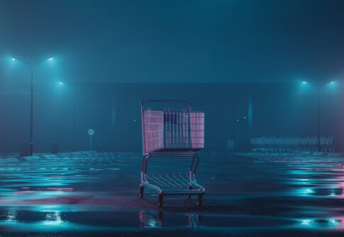 A shopping cart in an empty parking lot illuminated by neon lights in a foggy night