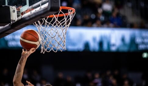 A basketball player reaching for the hoop with a ball