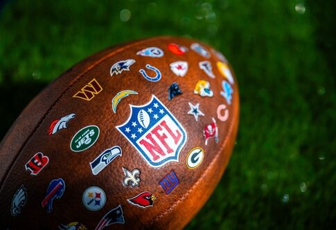 Close-up of an NFL football featuring various team logos on its surface