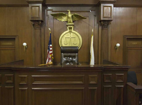 Judges bench in an empty courtroom, scales emblem above.