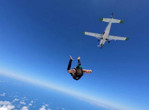 Skydiver jumping from airplane in clear blue sky