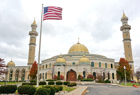 A mosque with a golden dome and minarets, featuring an American flag in front