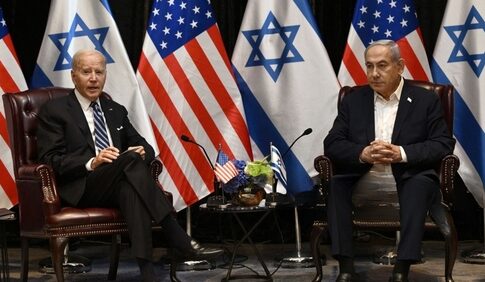 Two political leaders seated with flags in the background