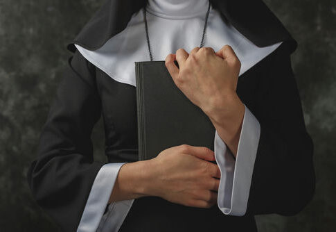 A nun in traditional attire holding a book close to her chest