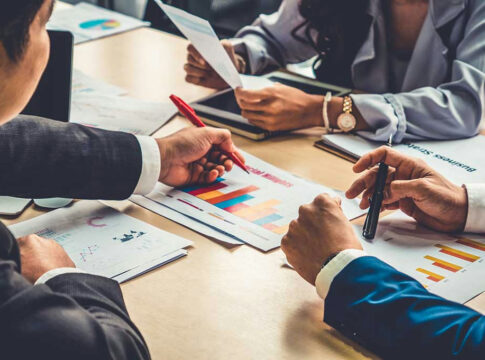 People discussing charts and graphs at a meeting.