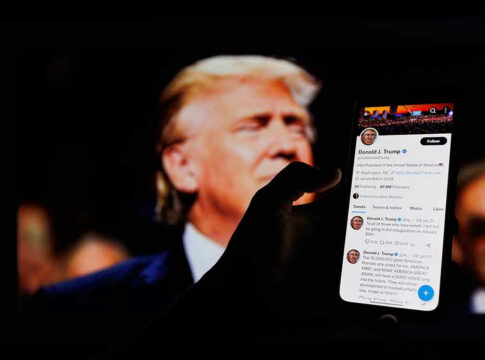 Hand holding smartphone displaying Twitter profile.