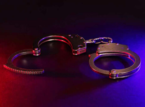 Handcuffs illuminated by red and blue lights.