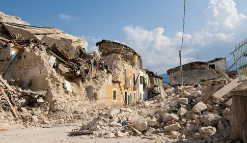 Rubble from collapsed buildings in earthquake-hit area. Clear sky.