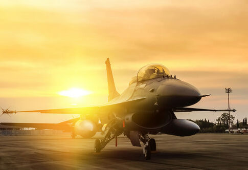 Fighter jet taxiing during sunset on an airstrip.